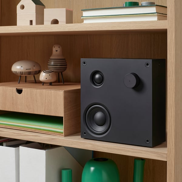 Bookshelf with VAPPEBY speaker, controls, books, and decor.