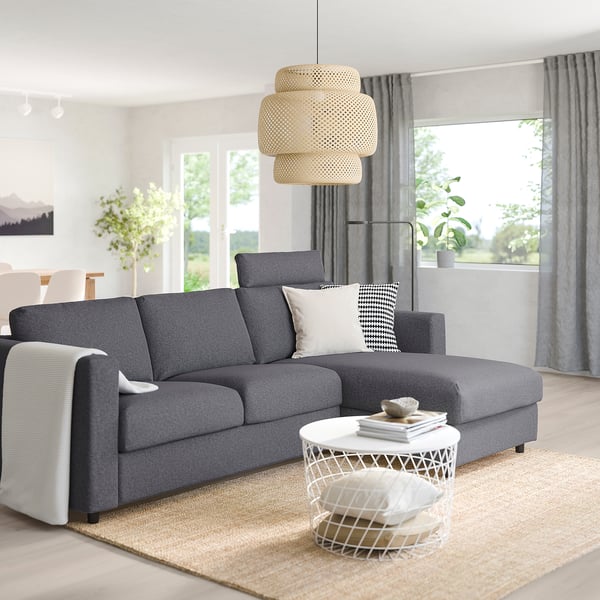 Modern living room with grey VIMLE sofa, chaise, pillows. Coffee table with books, large window, wooden floor, grey curtains, pendant lamp.
