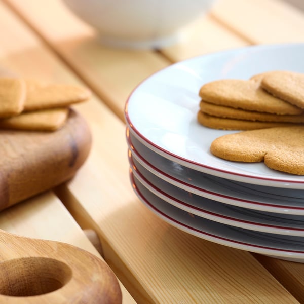 Stacked striped porcelain plates with heart-shaped cookies on top plate, set on wooden table.