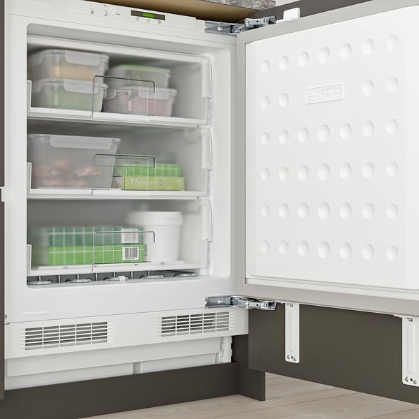 Open white under-counter freezer with three transparent drawers, vents at bottom, and adjustable feet visible.