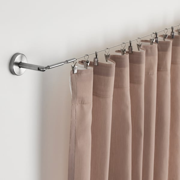 Varão de cortina com cortinas bege, fixado à parede com ferragens ajustáveis.