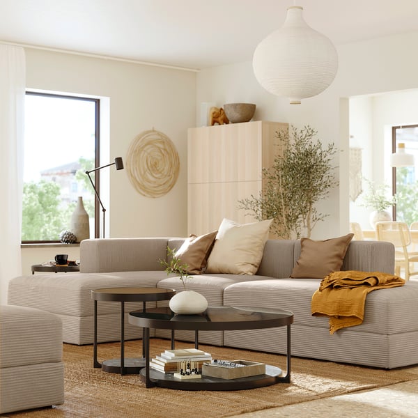Sala de estar moderna com sofá modular JÄTTEBO bege, mesa de centro de madeira e janela grande.