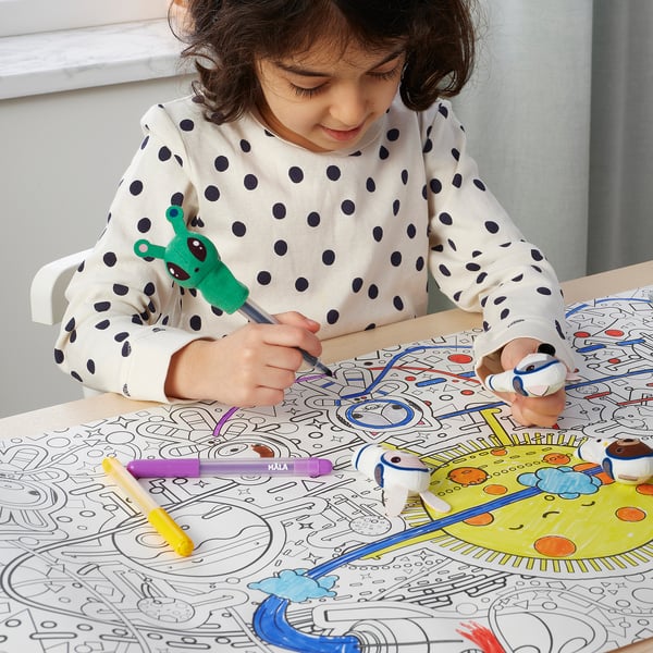 Child draws with markers on large space-themed colouring mat, using finger puppets.