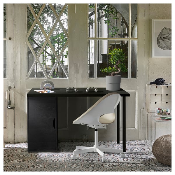Home office setup with ALEX dark brown desk and white chair, large window, plant, and patterned rug.