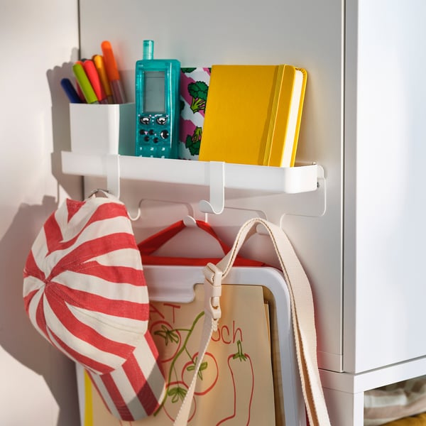 Hook rack with storage. Hangs on wardrobe frame. Holds items like bags, notebook, and pens.