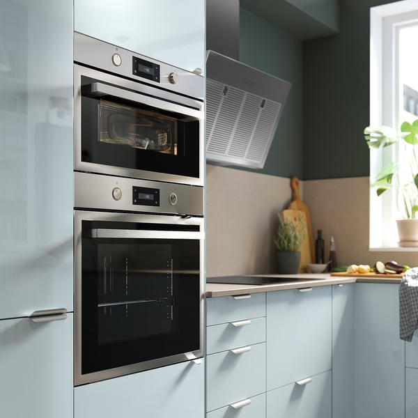 Modern kitchen built-in stainless steel double oven with digital controls, below a white vent hood.