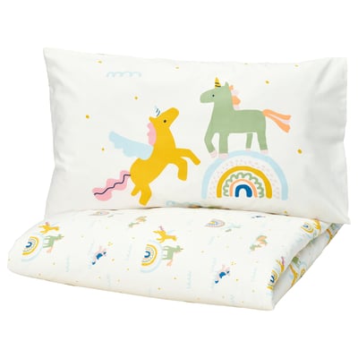 A white pillow with a cartoon unicorn and rainbow design and a matching white blanket with small unicorns and rainbows.