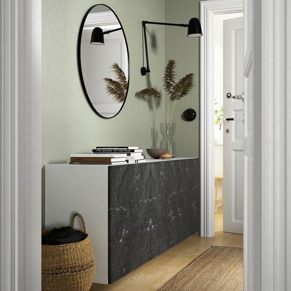 Modern entryway with BESTÅ storage, marble top, books, flowers, mirror.