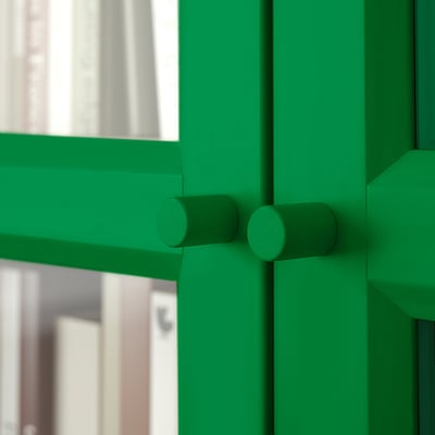 Green bookcase with glass doors, featuring robust design and adjustable shelves for versatile storage.