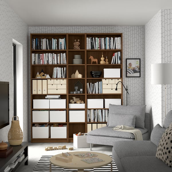Modern living room with BILLY bookcase, grey sofa, toys, and wall lamp.
