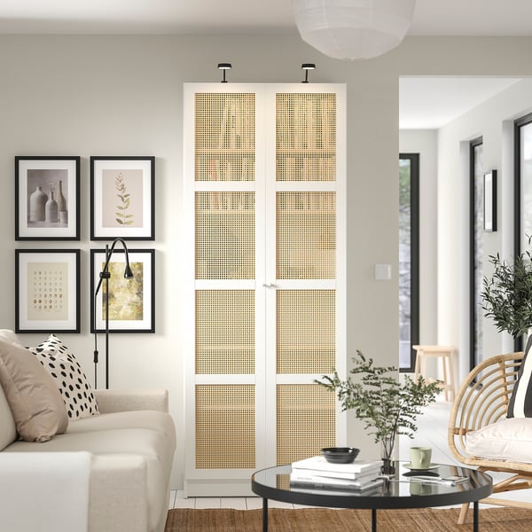 Modern living room with white walls, featuring a BILLY bookcase with beige bamboo doors, a beige couch, and dark wood coffee table.