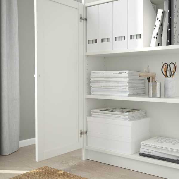 White BILLY bookshelf with adjustable shelves. Holds books and office supplies, wall-mounted for stability.