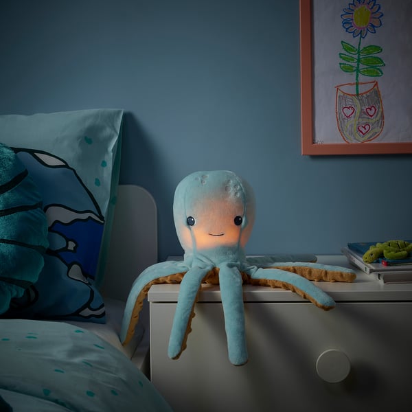 A soft octopus nightlight sitting on a bedside table, glowing gently, with a huggable design perfect for kids.