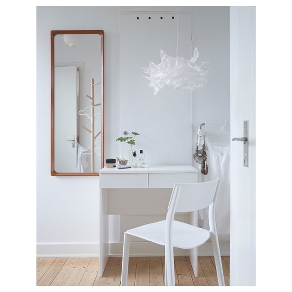Minimalist dressing table with integrated mirror and storage. White design with wooden accents. Includes a chair and decorative items.