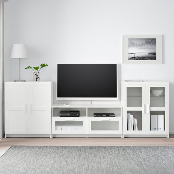 Minimalist living room: BRIMNES tv unit with large flat screen, flanked by cabinets, lamp, plant, rug, and art.