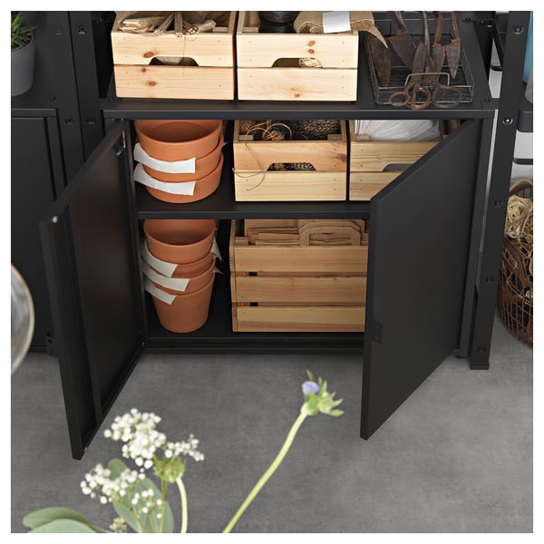 Black BROR storage cabinet with wooden crates and clay pots inside, organised with gardening tools on shelves.