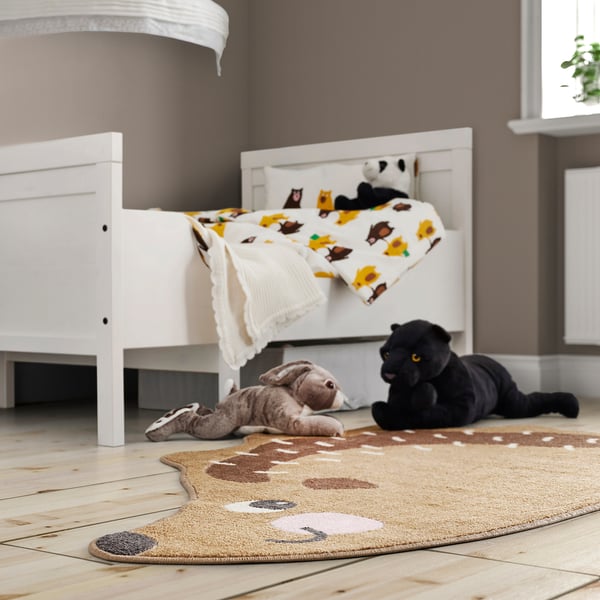 Kids room with BRUMMIG beige rug, featuring stuffed animals, under a small white bed.