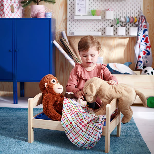 Child playing with stuffed toys in a colourful room.