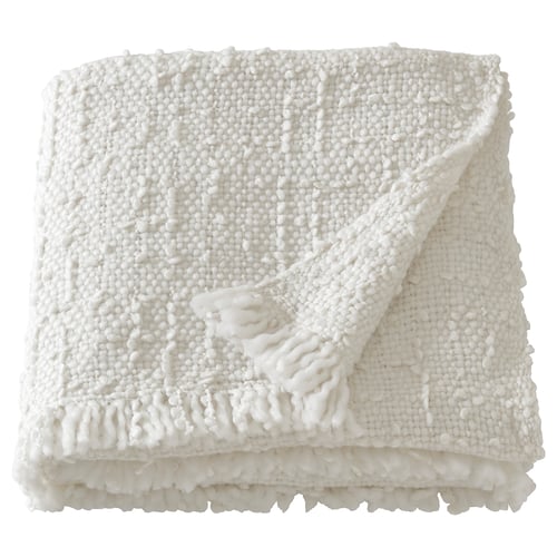 Folded white chunky knit throw blanket with fringe edges, made from recycled polyester.