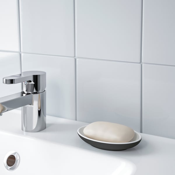 A modern bathroom sink with a chrome tap and a small dish holding soap.