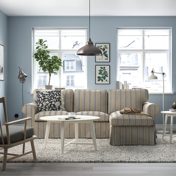 Cosy living room with EKTORP sofa, windows, coffee table, accent wall, rug, prints, side chair, lamp, and plant.