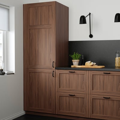 Modern kitchen with tall walnut-brown ENKÖPING cabinets, black countertop, black wall lights, and a small potted plant.