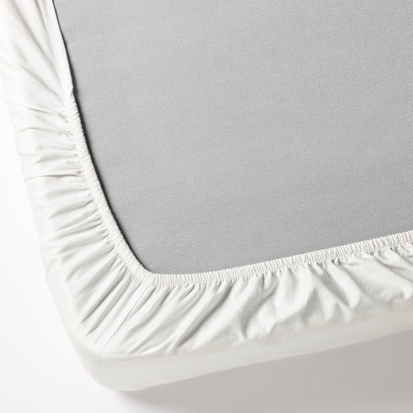 A fitted cotton sheet with elastic edges covering a mattress, demonstrating its secure fit.