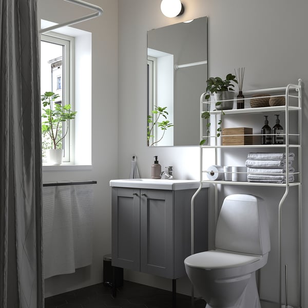 Modern grey bathroom featuring theFRÖSJÖN over-the-toilet storage shelf. It holds toiletries and toilet paper, standing between the sink and window.