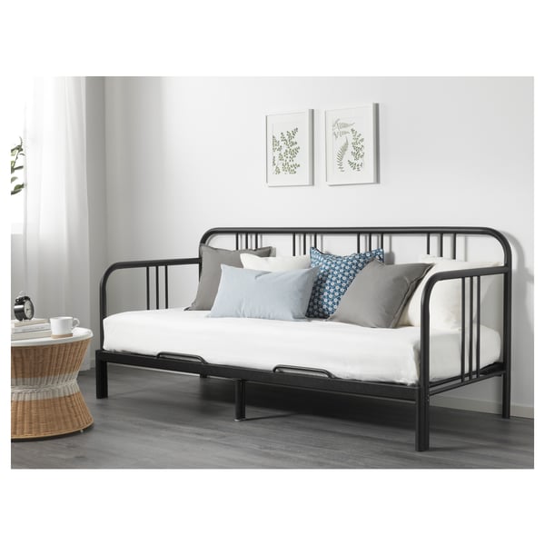 Modern black metal daybed with white mattress, grey and blue pillows, versatile for sleeping or lounging.