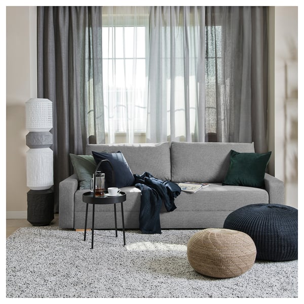 Modern living room with grey GRÄLVIKEN sofa, cushions, round pouffes, side table, and tall floor lamp by window.