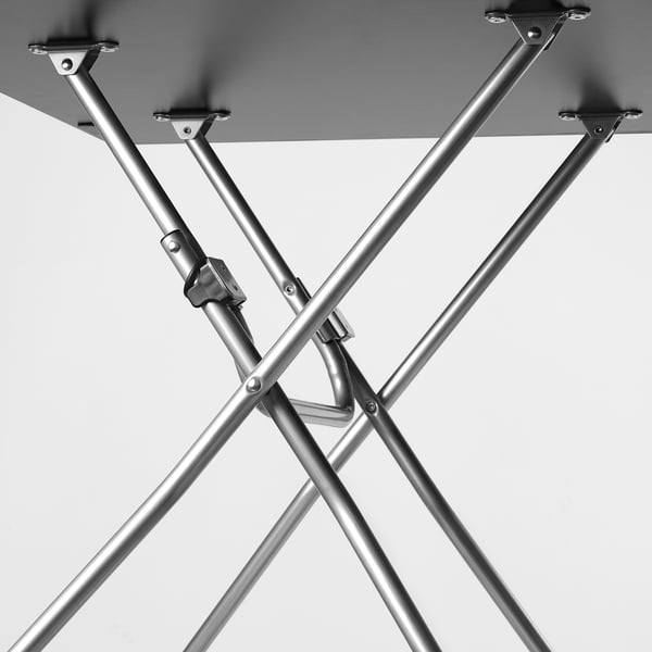 Black and white close-up of metal table leg joints. Sturdy, adjustable design with screws visible, emphasising durability and precision engineering.