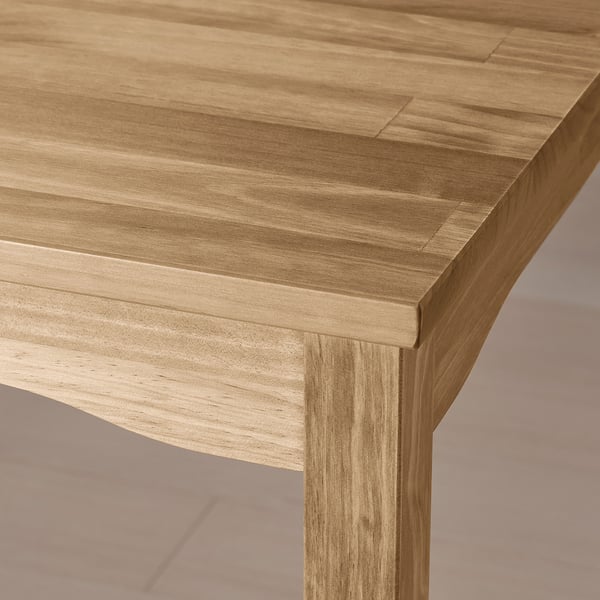 A close-up of a light wood dining table showcasing its smooth, natural finish and strong joinery.