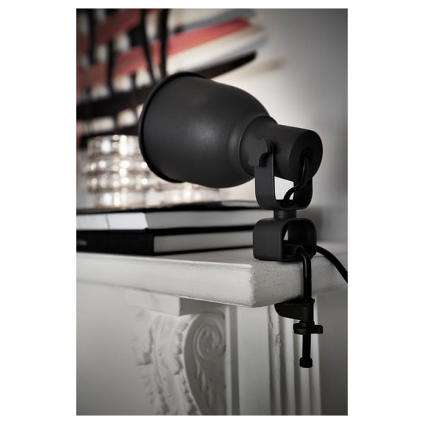 Black adjustable clamp spotlight on white surface, aiming upward.