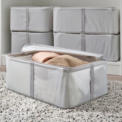 Storage box with lid, holding folded clothes, stacked neatly for organised storage.