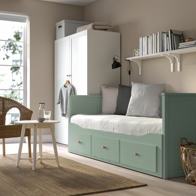 Modern small bedroom with HEMNES green day-bed, white wardrobe, and round table. Cosy, minimalist decor with soft lighting.