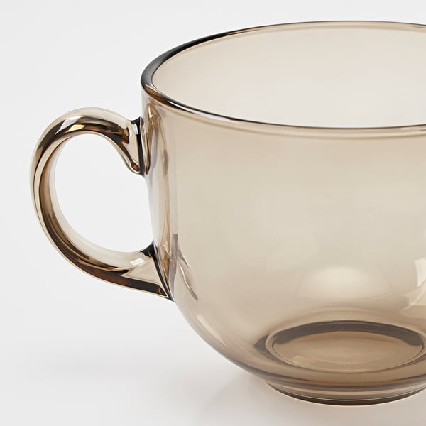 Amber-colored glass mug with a sturdy, elegantly curved handle, reflecting light, showcasing its clear and smooth finish.