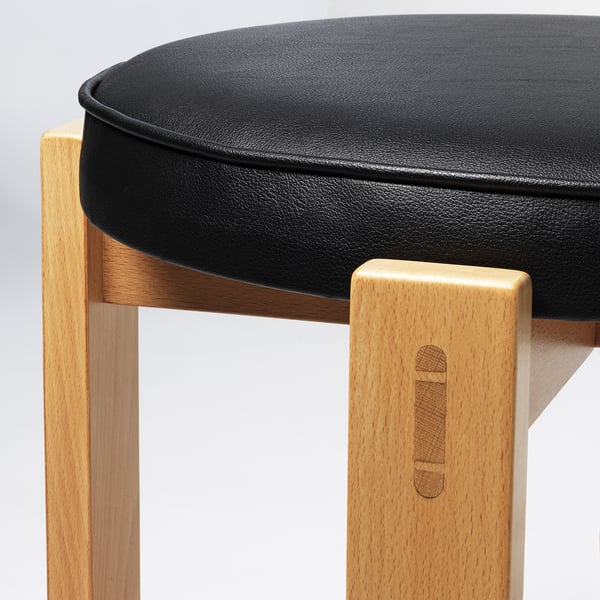 Modern stool with sleek black cushioned seat & sturdy wooden legs, showcasing quality craftsmanship.