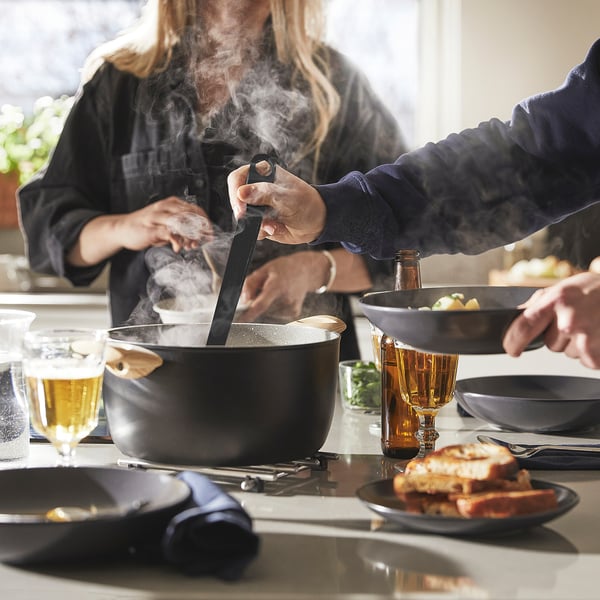 Person cooks in stylish pan with non-stick coating. Steam vent and comfortable handle visible.