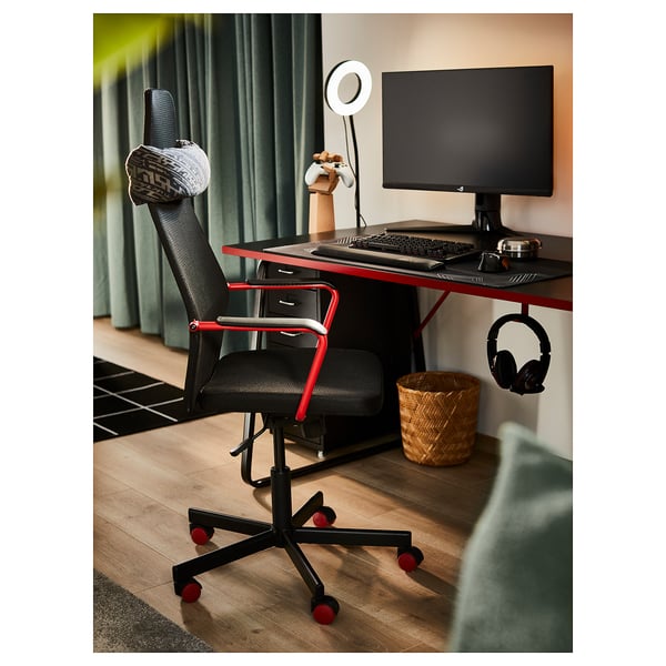 Modern gaming desk setup with black chair, monitor, keyboard, and headphones.