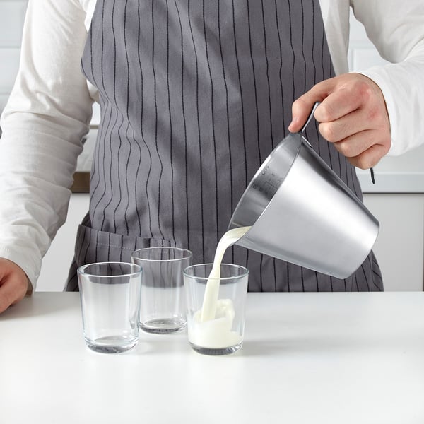 Person pours liquid from measuring pitcher into glass cups.