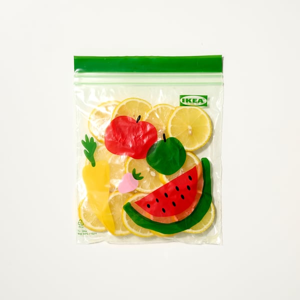 A colourful, transparent IKEA bag with a zip, containing toy fruits, suitable for organising items and leftovers.