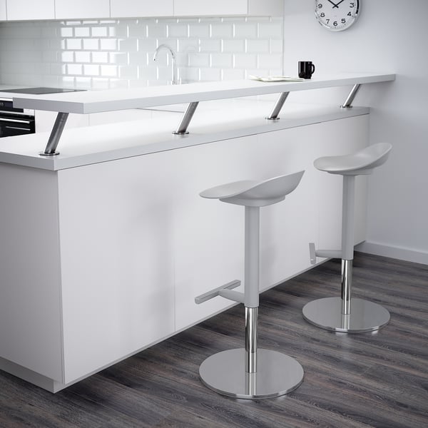 Modern kitchen with white counter, sink, tiled backsplash, two barstools, and a black mug.