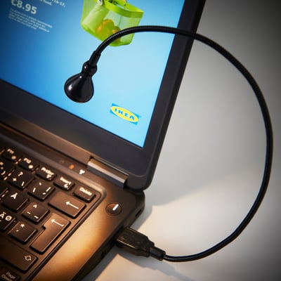 Laptop screen with a black ikea flexi-lamp attached, providing focused illumination.