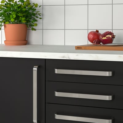Kitchen with black drawers, herbs, and pomegranate.