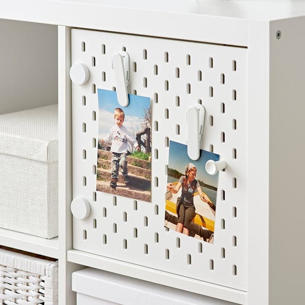 White KALLAX shelf with pegboard insert, displaying photos and accessories.