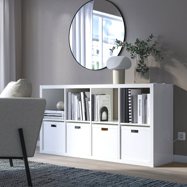 KALLAX shelf with books, mirror, chair, plant, lamp.