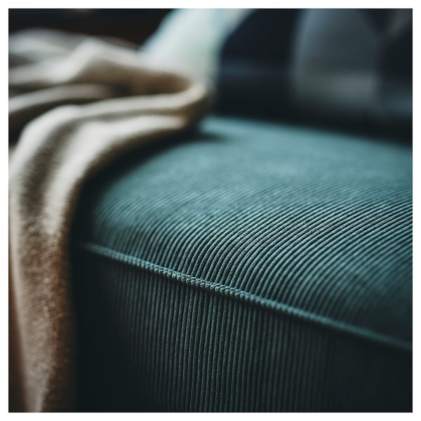 Dark teal corduroy sofa close-up, showcasing textured fabric & neat stitching; modern, comfortable design.
