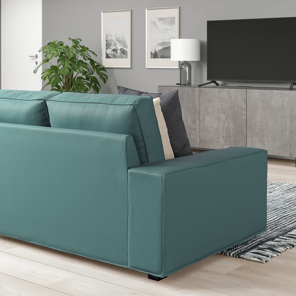 Modern living room with large green KIVIK sofa, grey cushions, tv, and plant. Sofas size matches tv stand and rug.