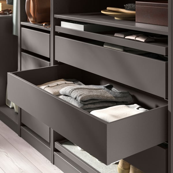KOMPLEMENT black drawer open, holding folded grey clothes.