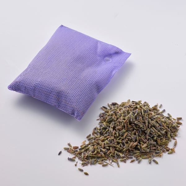A lavender-scented sachet and loose dried lavender on a white surface.
